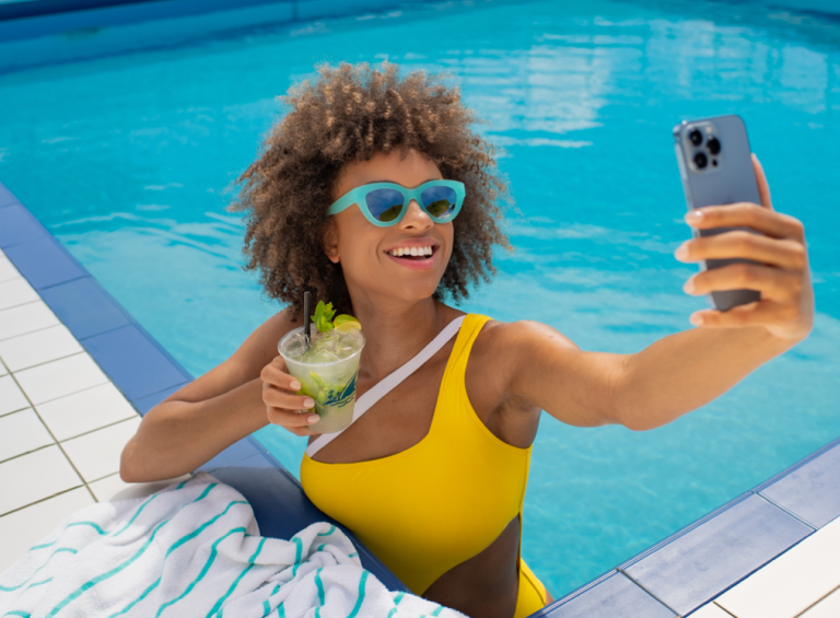 A Woman In A Pool Holding A Drink And A Cell Phone