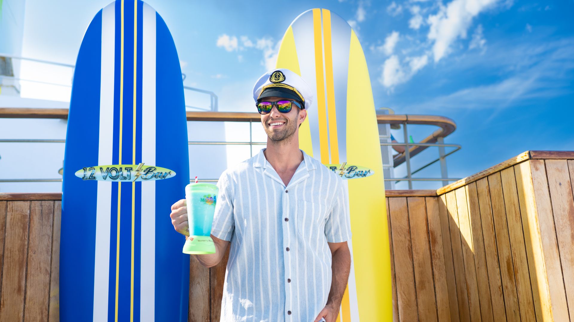 A Man Holding A Drink And Standing Next To Surfboards