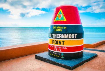 A Colorful Toy On A Platform With Southernmost Point Buoy In The Background