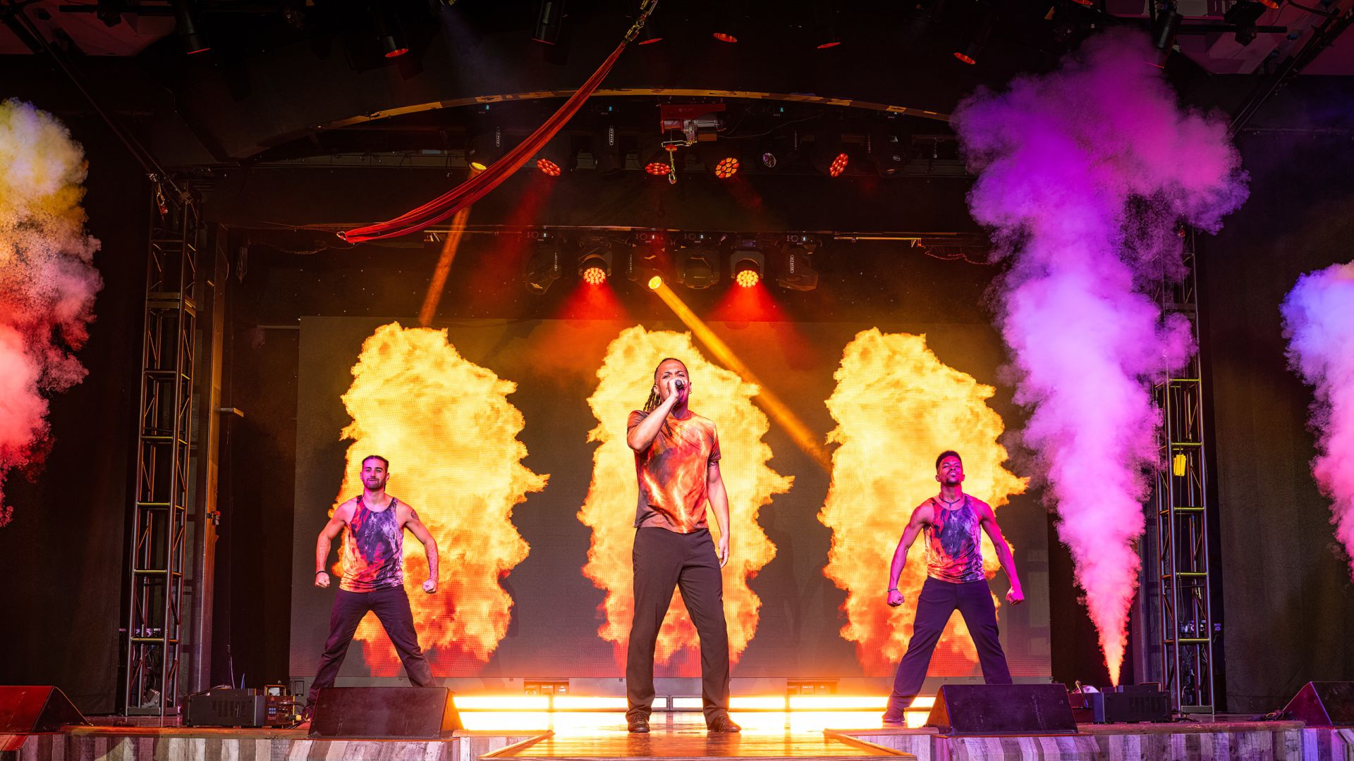 A Group Of People On A Stage With Fire And Smoke